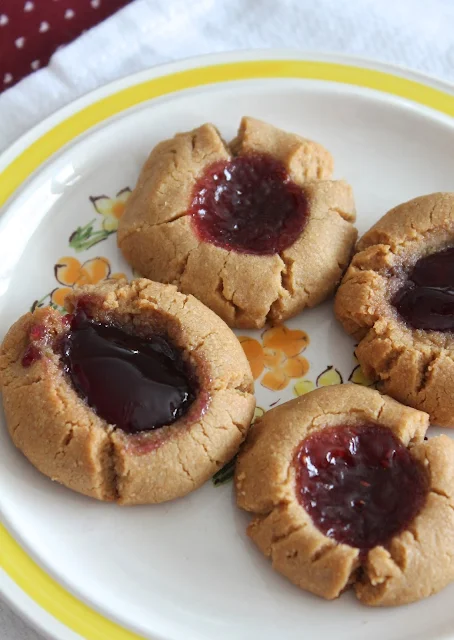 Thumbprint cookies on a plate with grape jelly and raspberry jam filling.