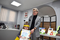 Zdjęcie przedstawia pracownika biblioteki wręczającego dyplom i nagrodę laureatowi Gminnego konkursu na strój bajkowy pt. „Bajkowy świat”.