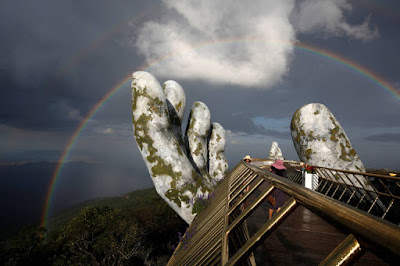 Mãos gigantes na Ponte Dourada no Vietnã com arco-íris ao fundo