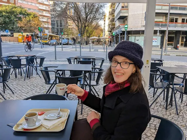 Jennifer from Sidewalk Safari drinking a coffee at a quiosque in Lisbon in February