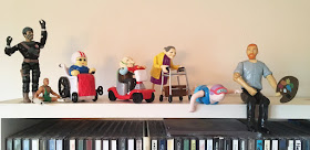 set of wind up toys depicting disability and art, sitting on shelf. photo by Artist and writer Corina Duyn