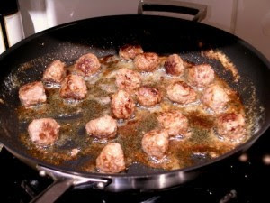 Swedish meat balls frying in a frying pan. Spaced in the pan so they do not steam.