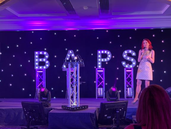 Carrie Grant in front of lit up BAPS sign