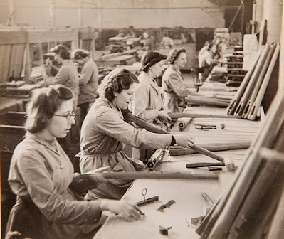 A sepia photograph of several women seated making rifle furniture