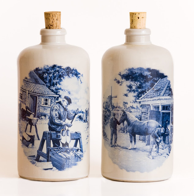 Two large Delft stoneware jugs with Dutch scenes in blue and white, and corked tops.