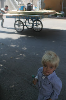 Anton with a blue lollipop and men pushing a cart in the background.