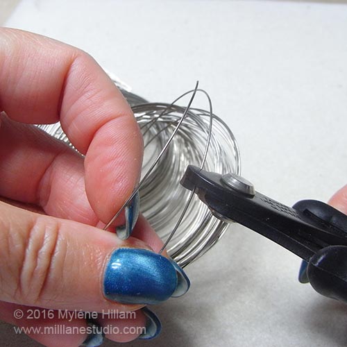 Using memory wire shears to cut a coil of memory wire.