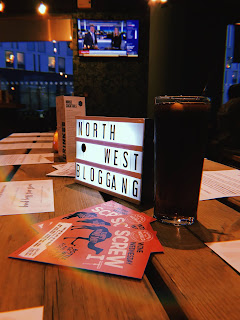 light box with letters spelling out north west blog gang on a wooden table with a pint of coke and some leaflets