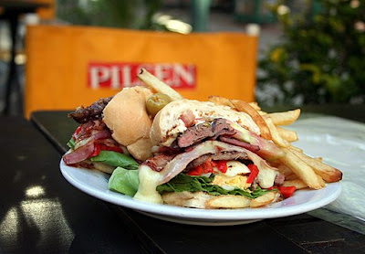 foto do sanduíche chivito - vemos o pão francês com carne, ovo, alface, ...,