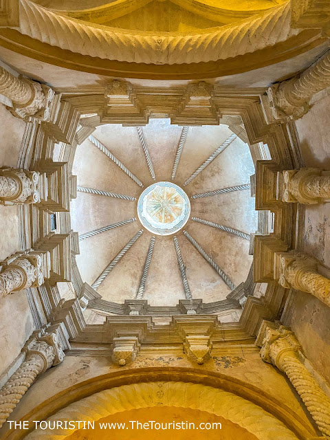 The ceiling in a giant sandstone Gothic-style cathedral, encircled by eight sandstone pillars.