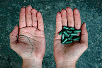 Dos manos, una ofrece pastillas verdes, a elegir entre ambas