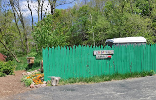 a bright teal fence with a sign reading "Children's Garden" provides the entrance to the childrens garden at Lauritzen Gardens