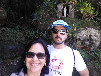 Casal Hibisco com Whey, ao fundo imagem religiosa numa gruta de pedra