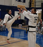 A black belt lady breaking with a jump front kick