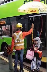 A foreign worker giveing shelter with an umbrella.at Sengkang East Way on Monday.