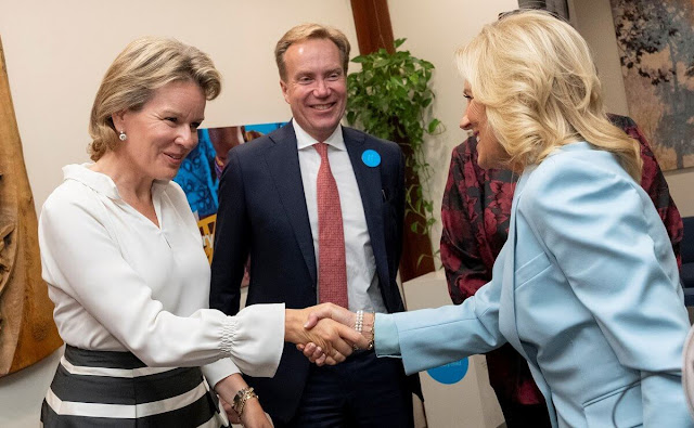 Queen Mathilde wore an orange silk dress, jumpsuit by Natan, and a stripe skirt and white silk blouse by Natan