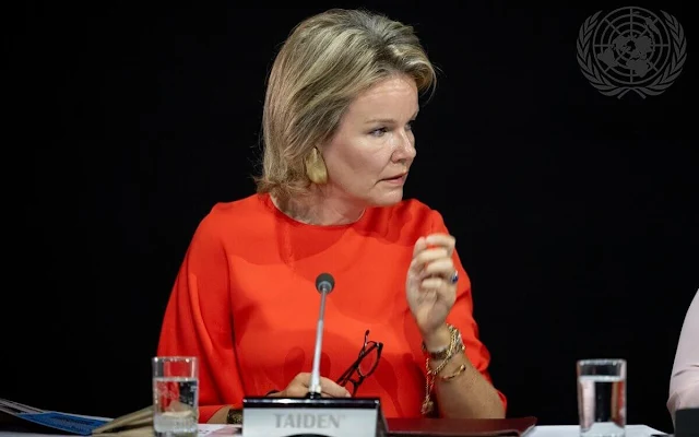 Queen Mathilde wore an orange silk dress, jumpsuit by Natan, and a stripe skirt and white silk blouse by Natan