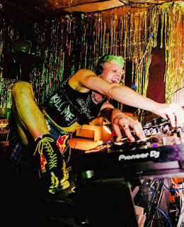 DJ Harry Gay at work in his booth and wearing a punk style outfit while revelling in the Club atmosphere
