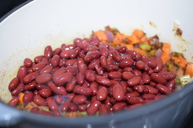 The kidney beans being added to the dutch oven.