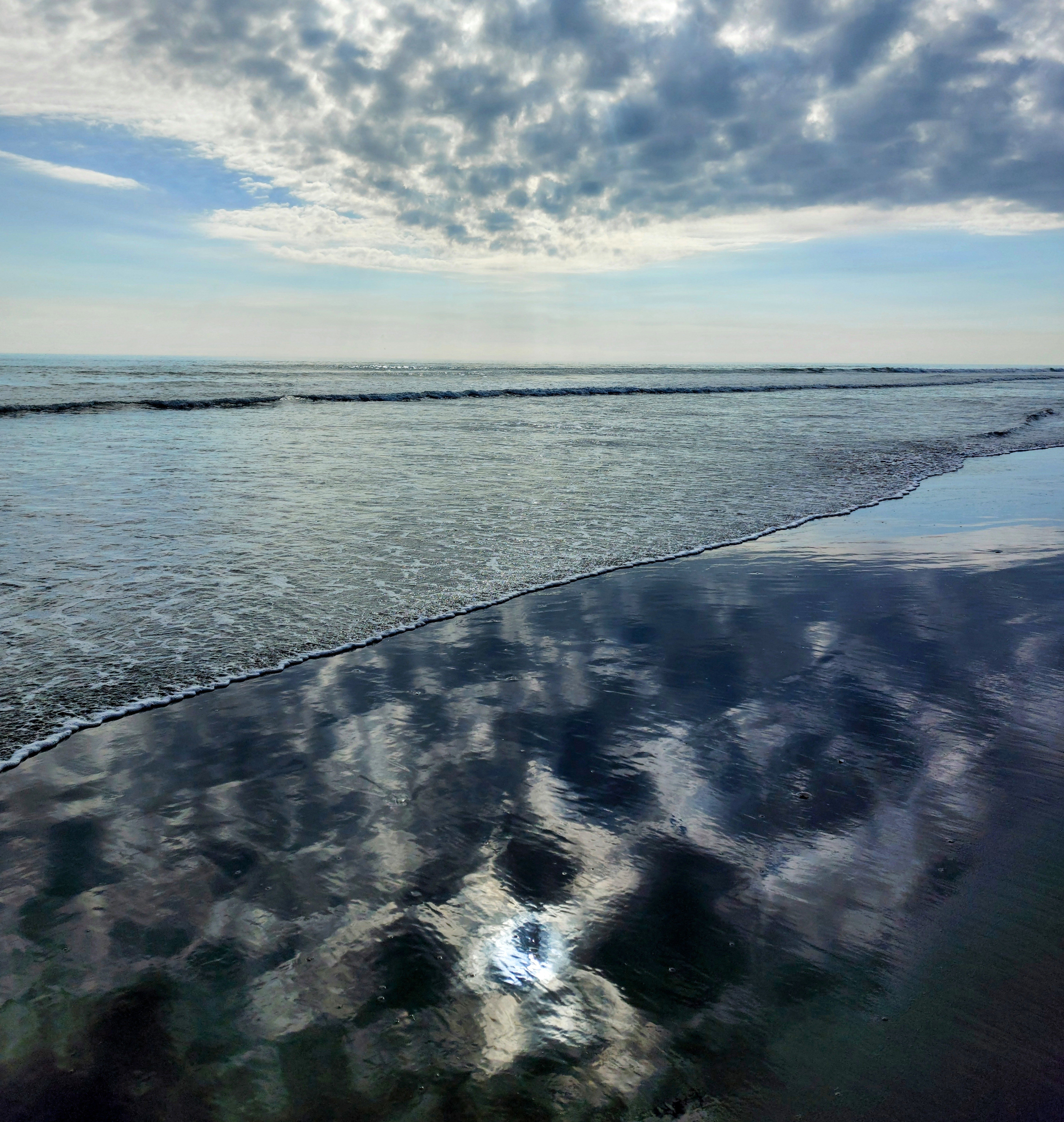 Cubist reflection of the cloud and sun on Waitārere Beach swash with the horizon in the middle of the photo. Is this a good description or just useless, let me know by leaving a comment.