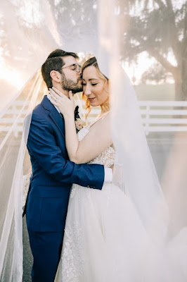 groom kissing bride on the forehead under veil