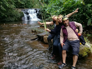 Turistas con coronas de hojas de palma disfrutando de las refrescantes cascadas de Yanayaku durante un paseo por el exuberante bosque, en medio de risas y momentos inolvidables.