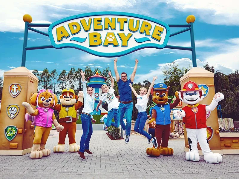 A sign saying adventure bay with an excited family and people dressed up as Paw Patrol dogs, image used with permission from Movie Park website