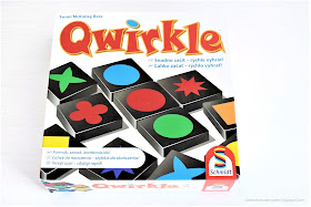 na zdjęciu opakowanie gry qwirkle, duże, kwadratowe, z czerwonym napisem i ilustracja kolorowych klocków - elementów gry