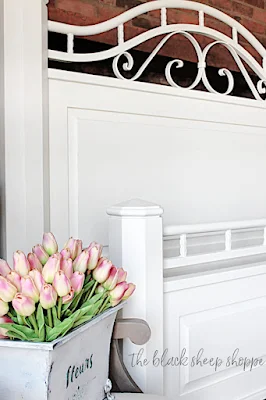 Pink tulips in container next to painted bed frame.