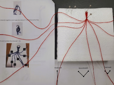 Instructions for a one-twelfth scale miniature macrame plant hanger, with the hanger pinned to a styrofoam board next to it with the yarn separated out.