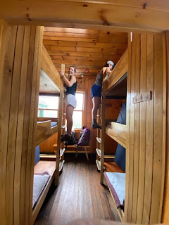two girls climb up to the top (3rd bed) bunk in AMC hut
