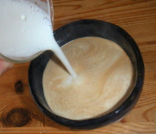 Shows steamed milk being added to make a latte