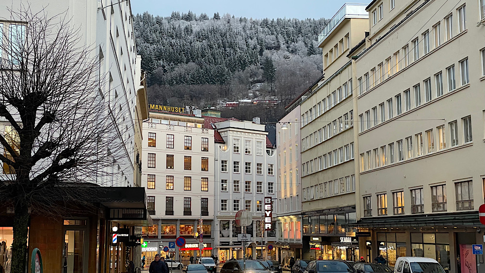 A view of distinctive four-storey shops in Bergen's shopping precinct with a snowy forest in the background | Bergen, Norway