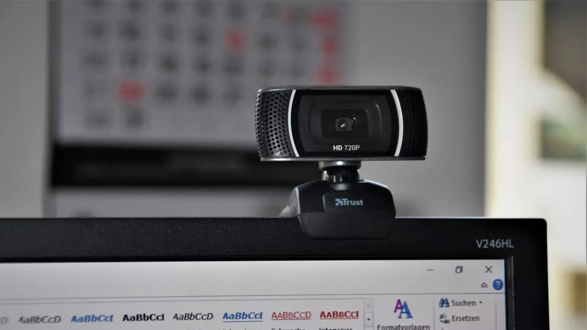Black webcam sitting on top of a computer screen.