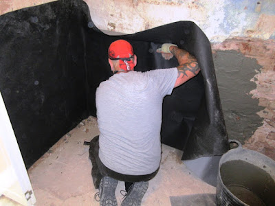 Damp man applying black damp-proof membrane