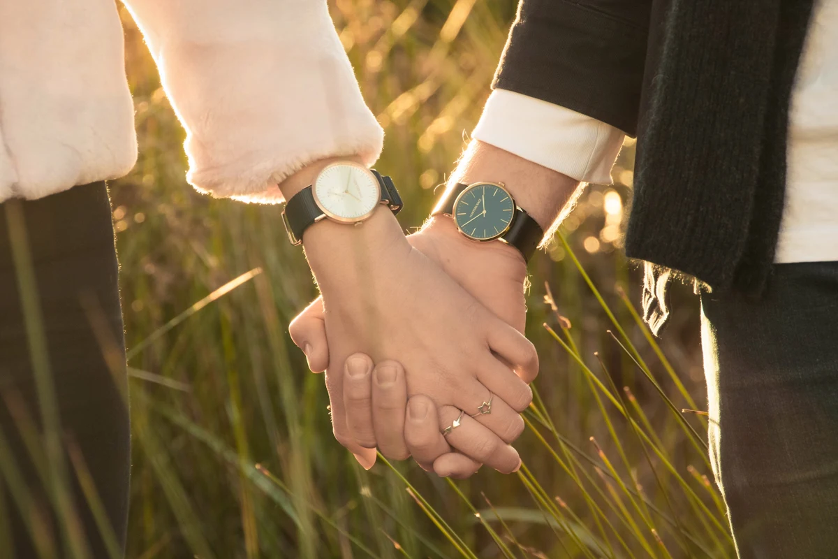 man and woman hold their hands together and wear watch on their wrtists