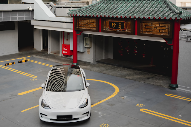 Tesla model Y parked in front of Chinese building, learn a trade, stocks to buy