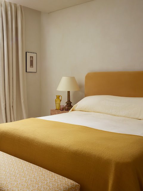 mustard bed linens with matching upholstered fabric headboard, clear colored glass vases