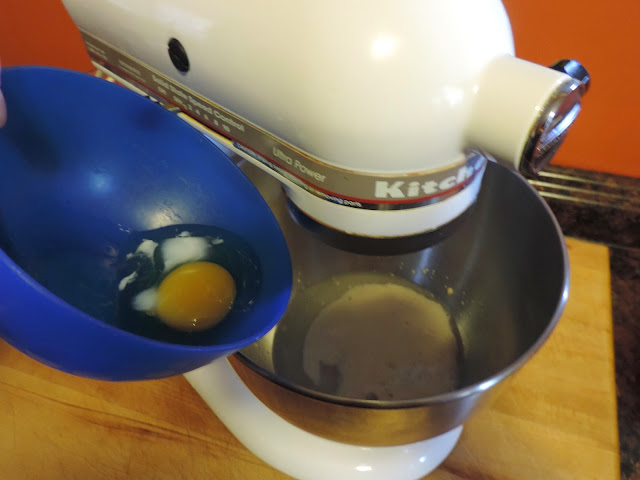 An egg being added to the yeast in the Kitchenaid mixer.