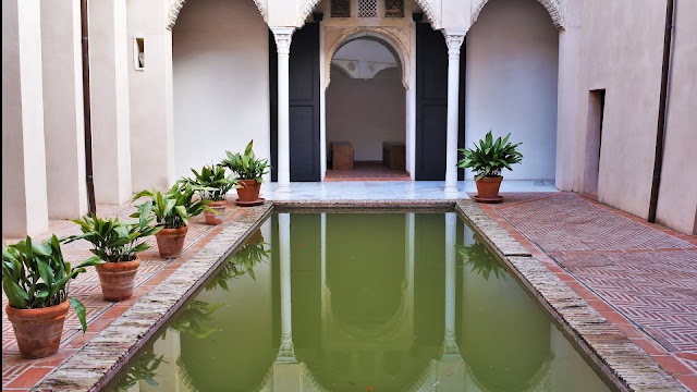 Patio interior de una casa árabe con una acequia y arcos con columnas.