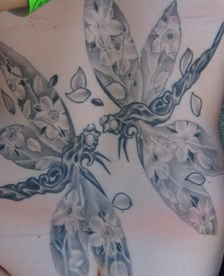 Two dragonflies with flowers image on their wings tattoo.