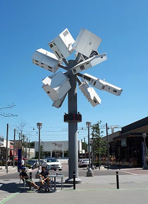 A sculpture resembling a dandelion puff but with many suburban-style house models arrayed in a starburst pattern at the top