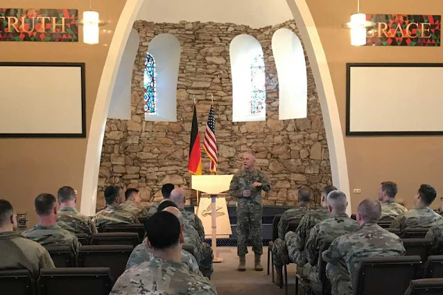 Chaplain (MG) Tom Solhjem talking to Service Members sitting in pews in church