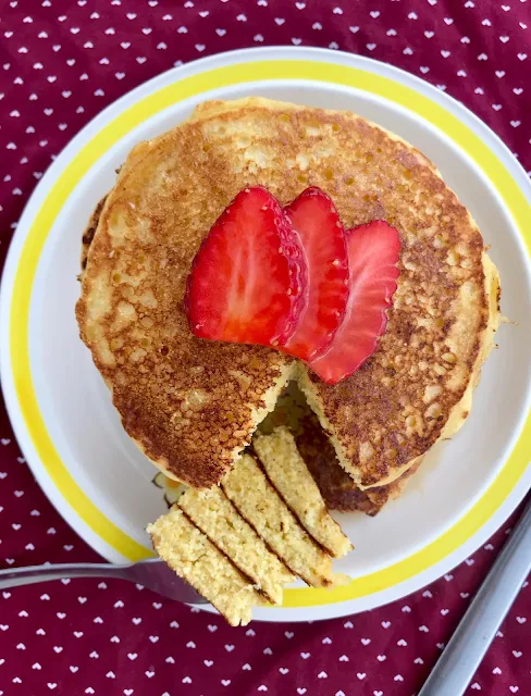 Bite on a fork from a stack of cornmeal griddle cakes.