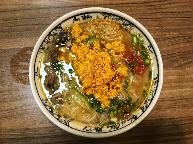 a bowl of Bún Cá, or Fish Noodle Soup in Hanoi, Vietnam with lots of fresh healthy vegetables