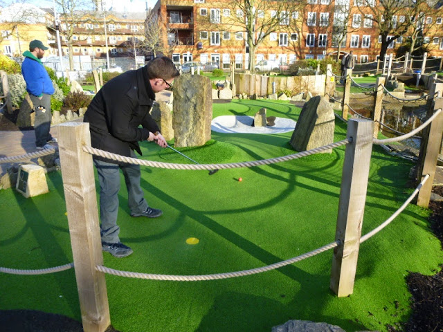 Playing the Putt in the Park mini golf course in London as Pat Sheridan from the Putting Penguin looks on