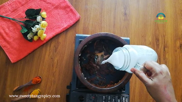 Pouring thin coconut milk into the earthen pot filled with sautéed ingredients.