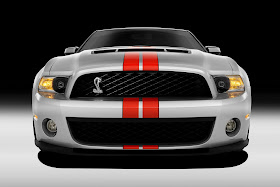 Front view of white 2011 Ford Shelby GT500 with red stripes and Cobra emblem in grille