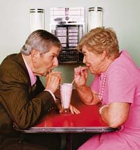 old couple dining together, eating from the same glass with straw