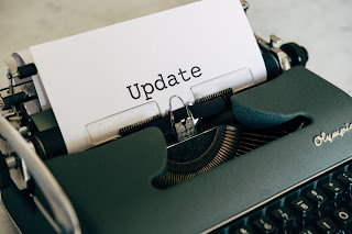 A typewriter with a piece of white paper spooled into it.  The paper includes one word, "Update".